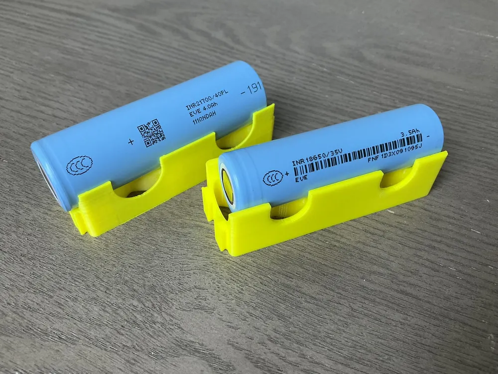Two blue cylindrical lithium-ion cells resting in yellow holders.